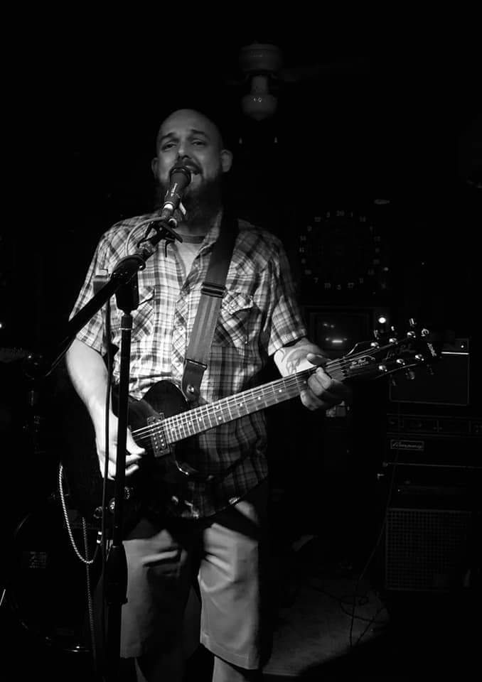 Black and white live photo of Scott Womack singing and playing guitar