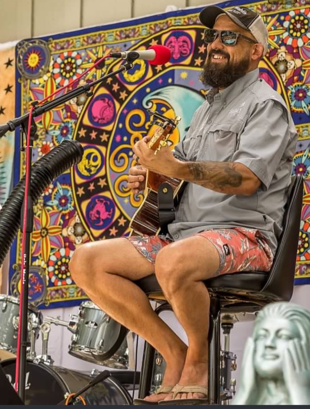 Scott Womack smiling while performing acoustic guitar at an outdoor festival