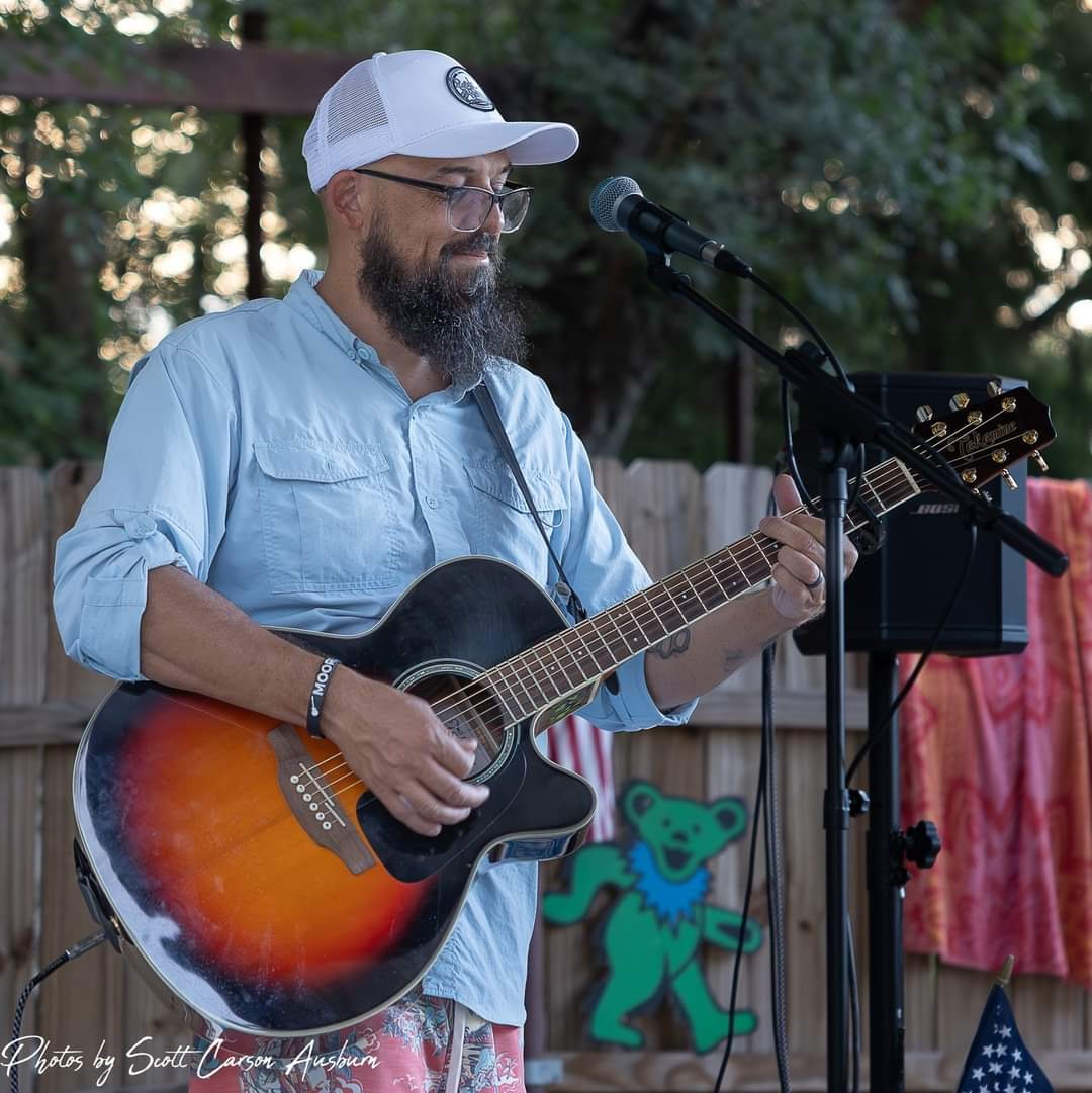 Scott Womack playing acoustic guitar outdoors